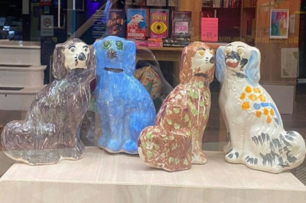 Four ceramic, brightly decorated Staffordshire Pot Dogs on display in a shop window